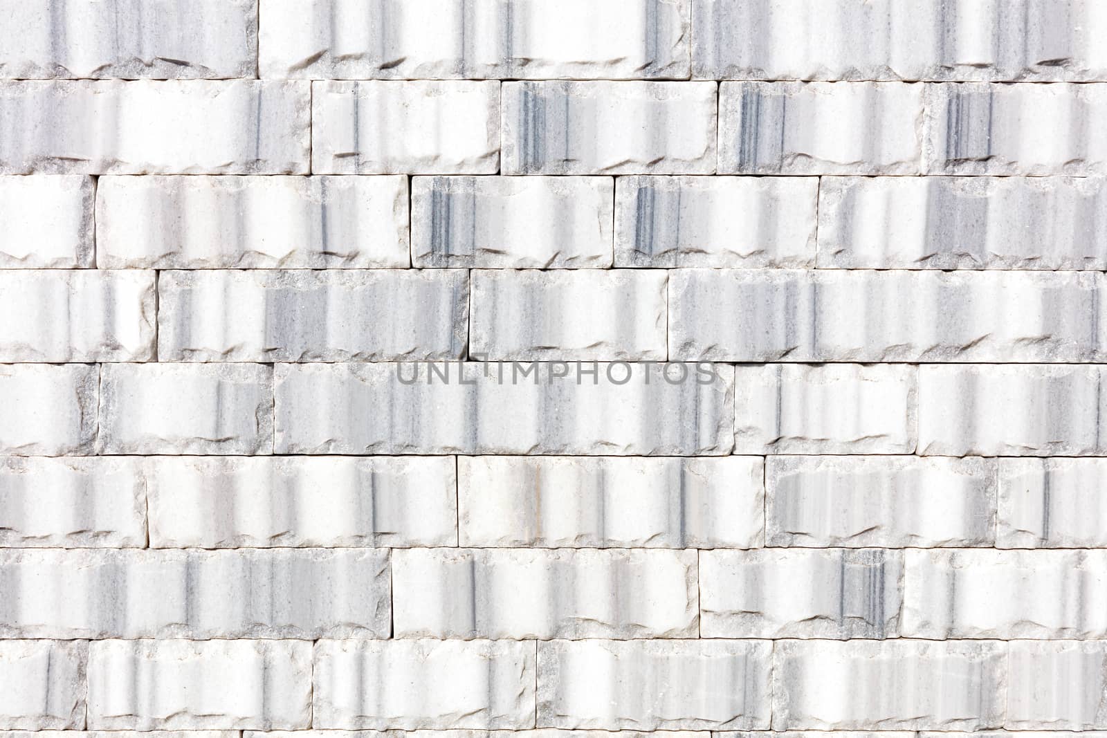 Wall background and texture of gray marble tiles chipped around the perimeter, close-up.
