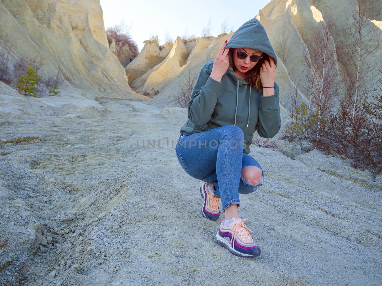 Hiker on mountain top with smartphone. Woman is standing and taking a picture on smartphone. Abandoned Quarry Of Rummu, Estonia. Scenic View Of Land Against Clear Blue Sky. Panoramic View.