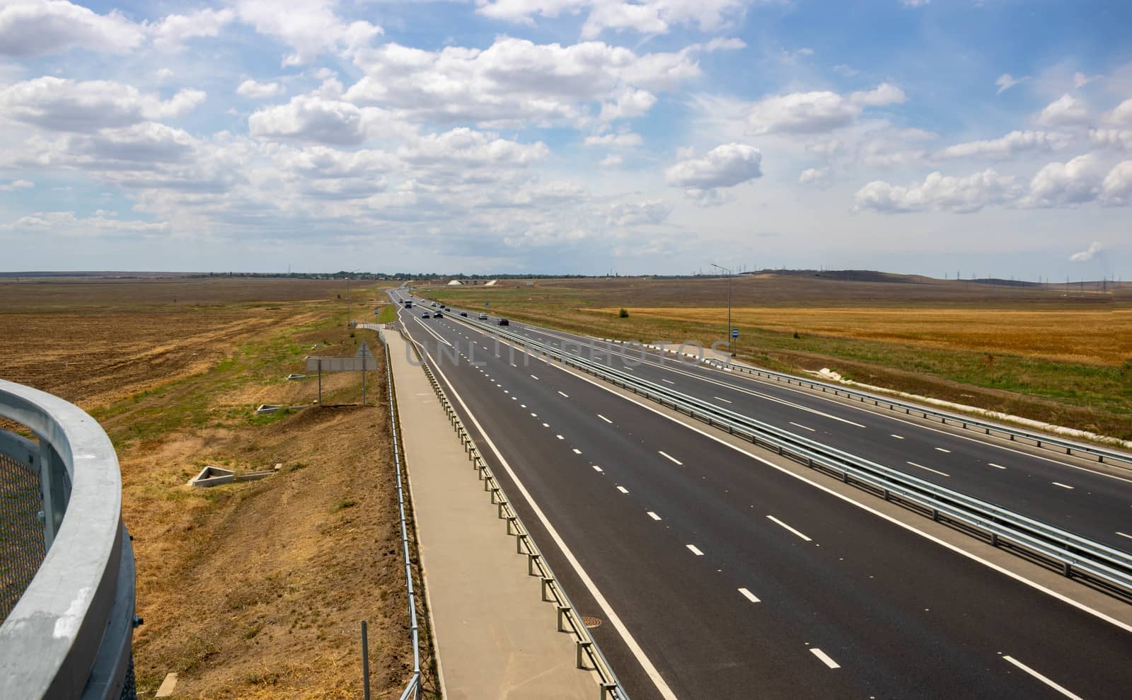 highway in the steppe against the blue sky, a long road stretching into the distance. by lapushka62