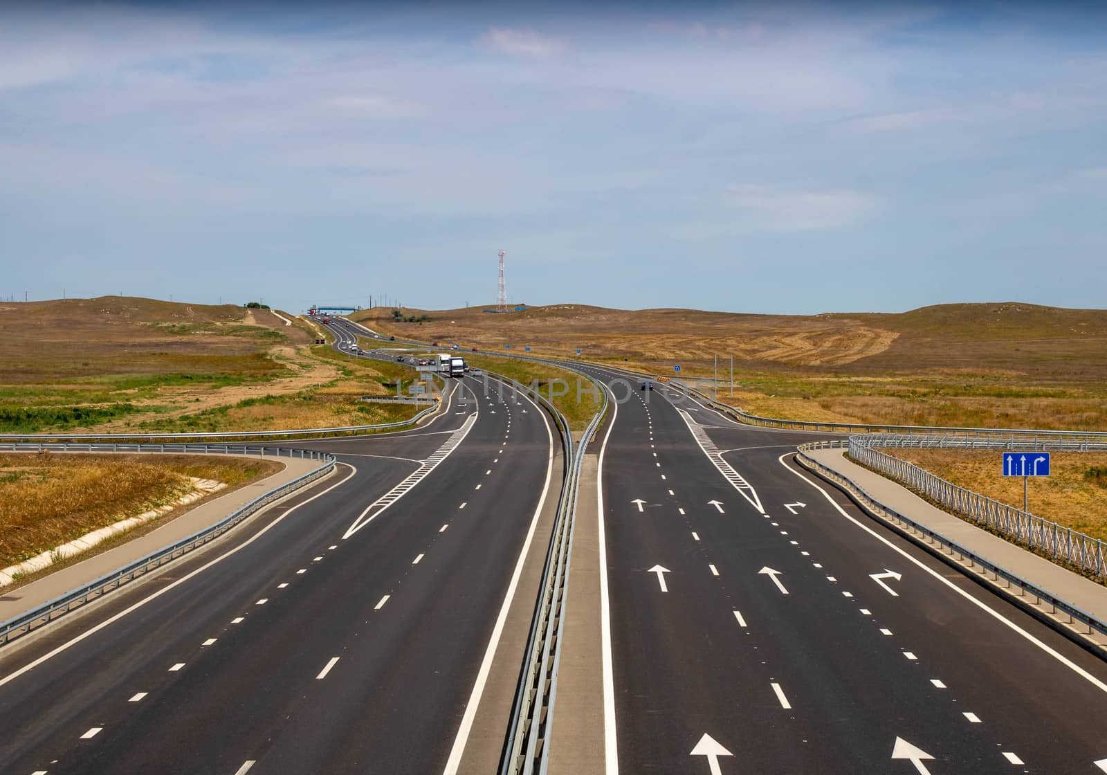 highway in the steppe against the blue sky, a long road stretching into the distance.