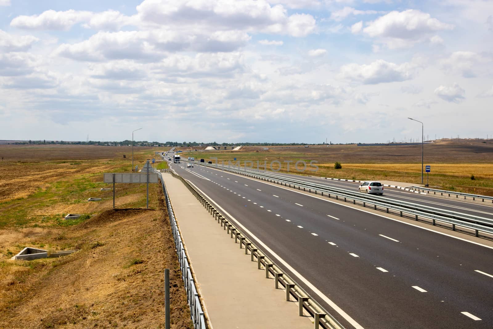 highway in the steppe against the blue sky, a long road stretching into the distance. by lapushka62