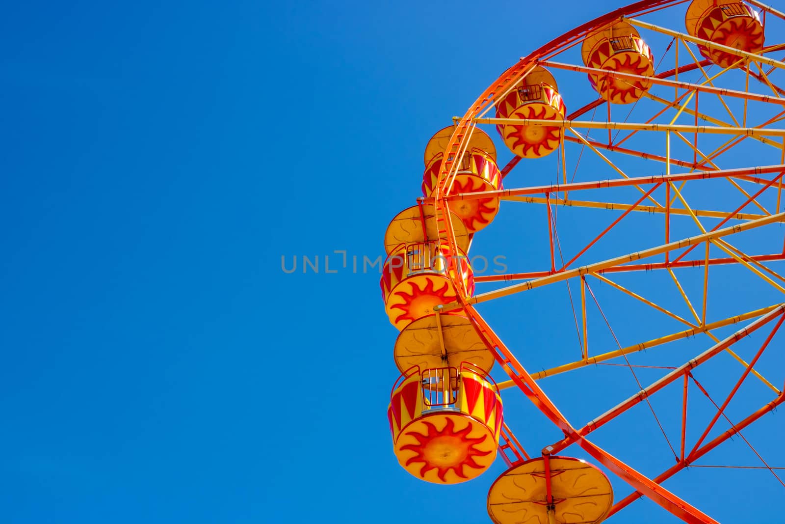 Yellow Ferris Wheel against a blue sky. Space for your text