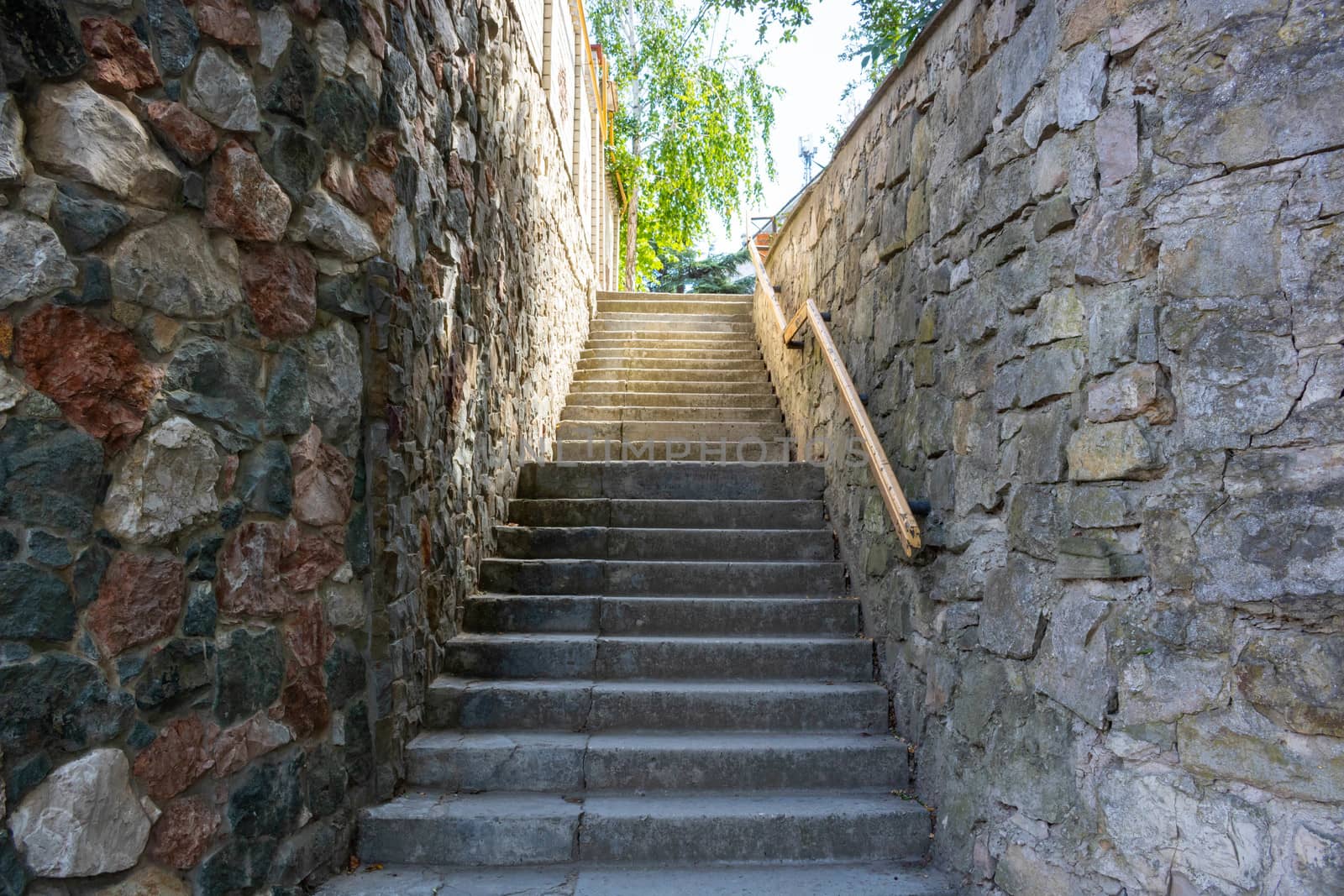 A stone staircase with a railing leading up.Summer day. by lapushka62