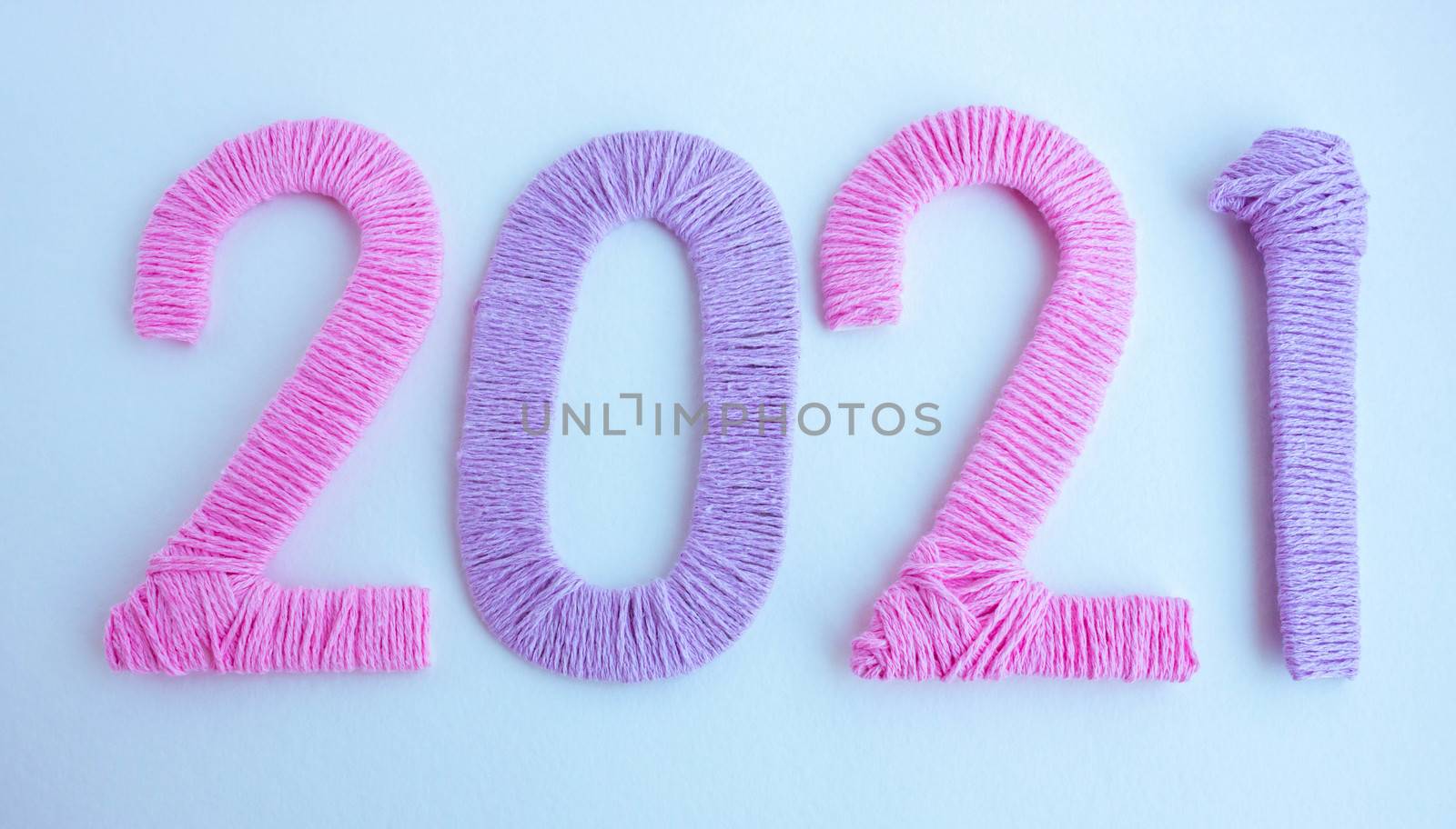 The numbers 2021 are made of pink and lilac threads on a white background. The concept of a New year.