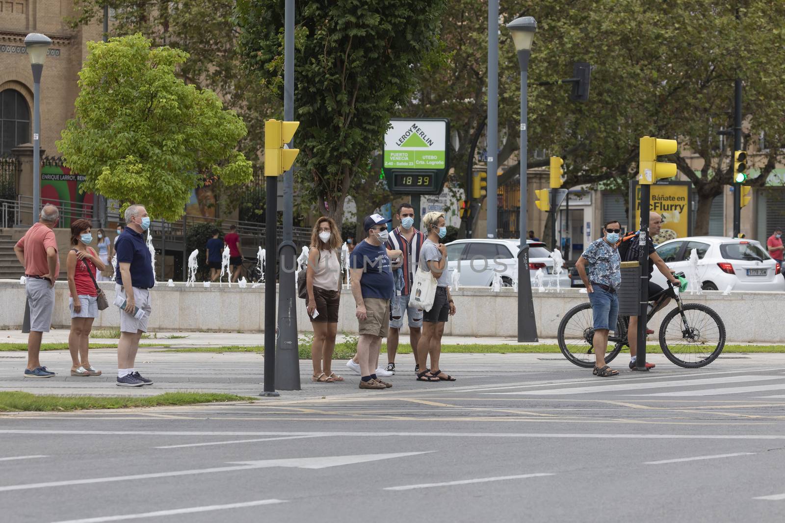 Zaragoza, Spain - August 18, 2020: People waiting in a crosswalk with face masks by alvarobueno