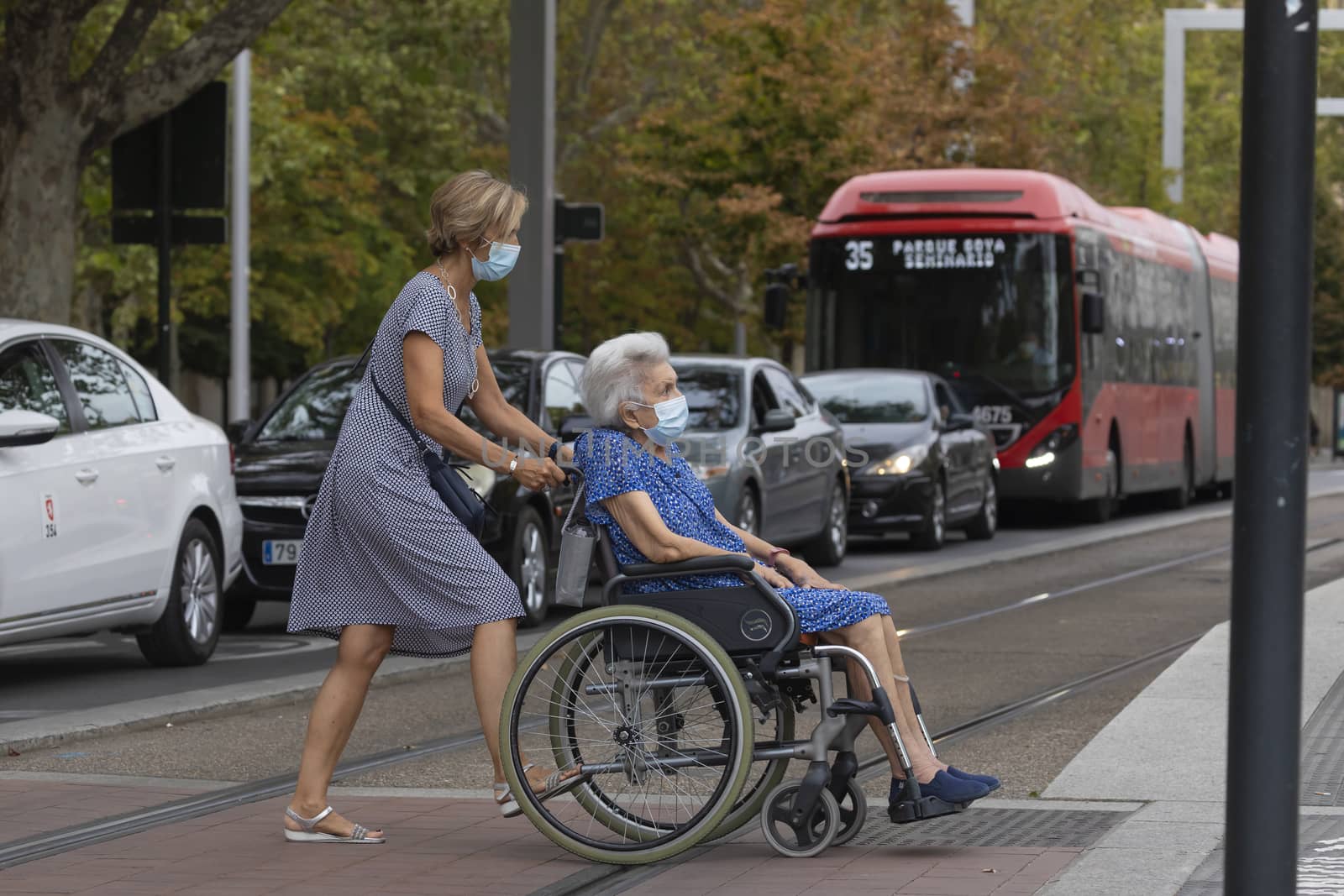 Zaragoza, Spain - August 18, 2020: Elderly woman in wheelchair wears face mask, due to the coronavirus pandemic, in the central area of Zaragoza.