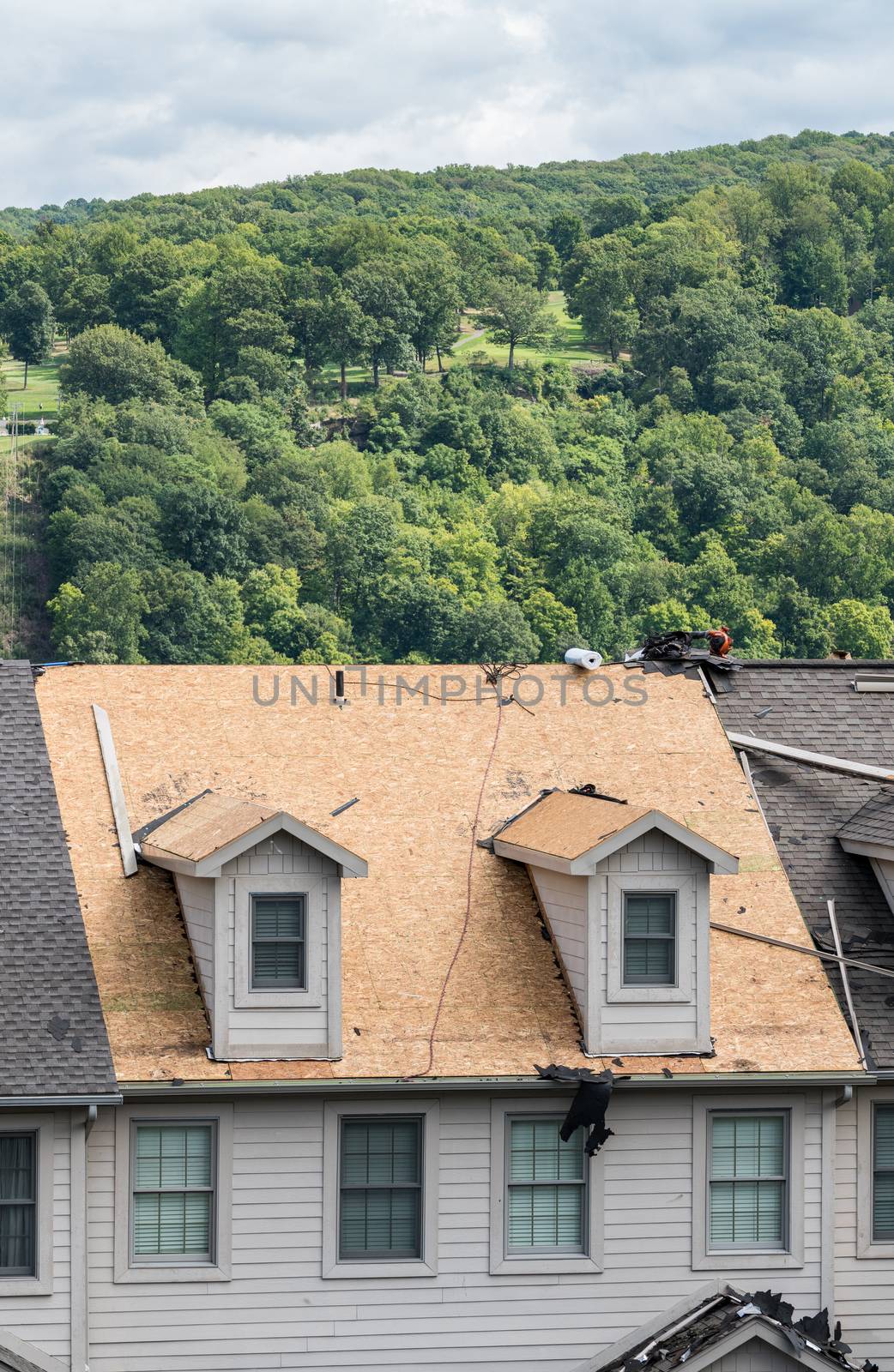 Roofing contractor has removed all the old tiles from townhouse roof before replacing with new shingles