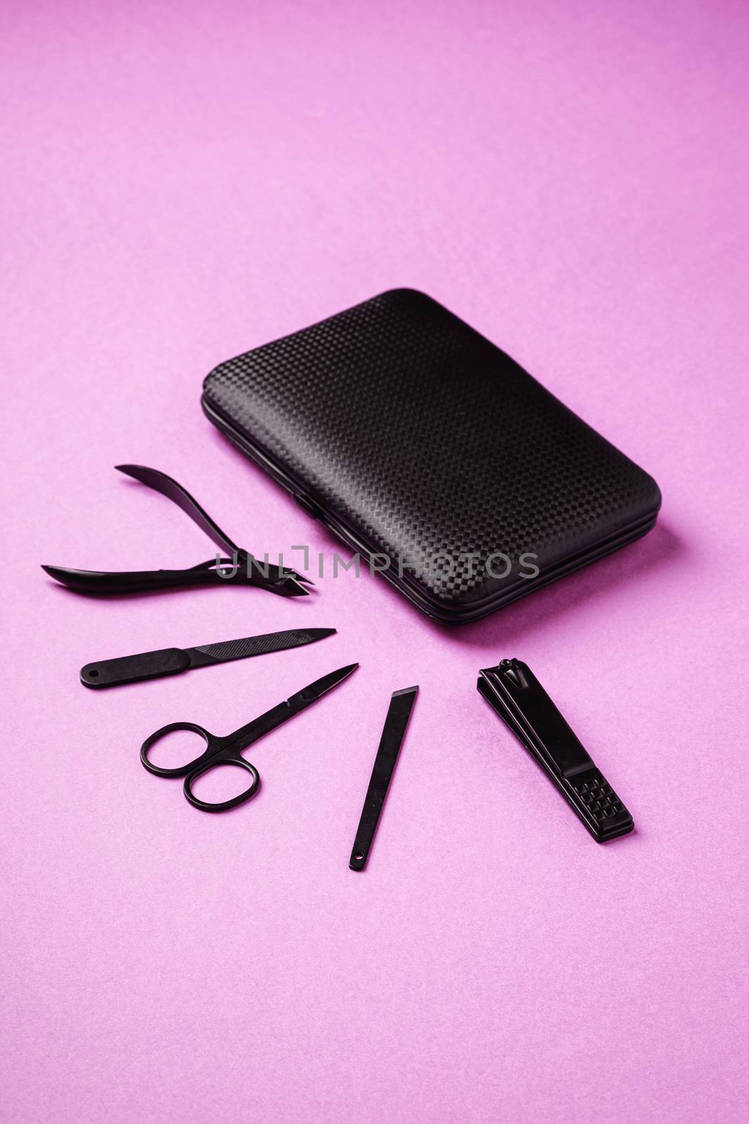 Set of manicure and pedicure tools and accessories near to case, angle view, pink background