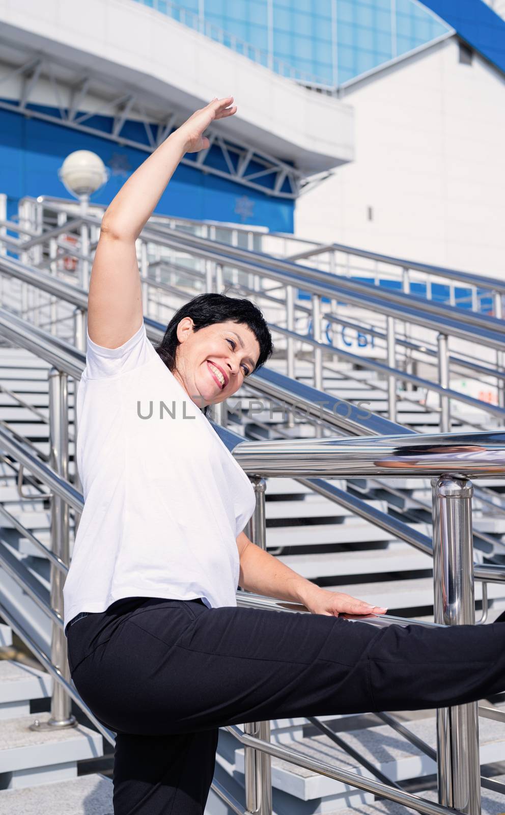 Sport and fitness. Senior sport. Active seniors. Smiling senior woman doing stretching outdoors on urban background