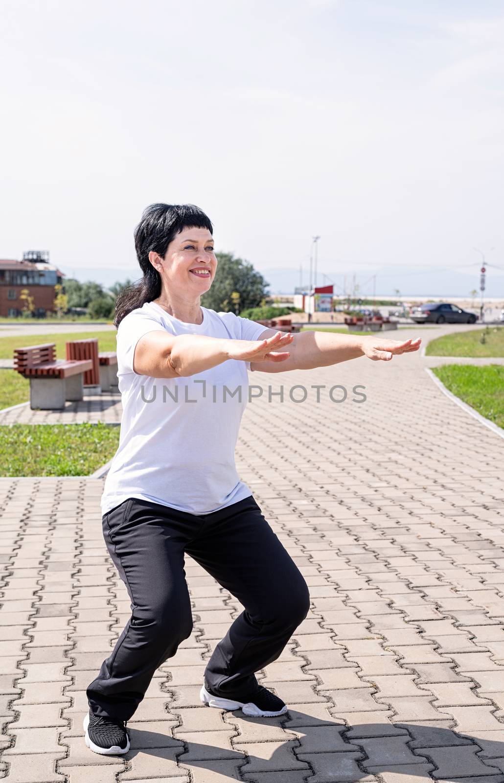 Sport and fitness. Senior sport. Active seniors. Smiling senior woman squatting outdoors in the park