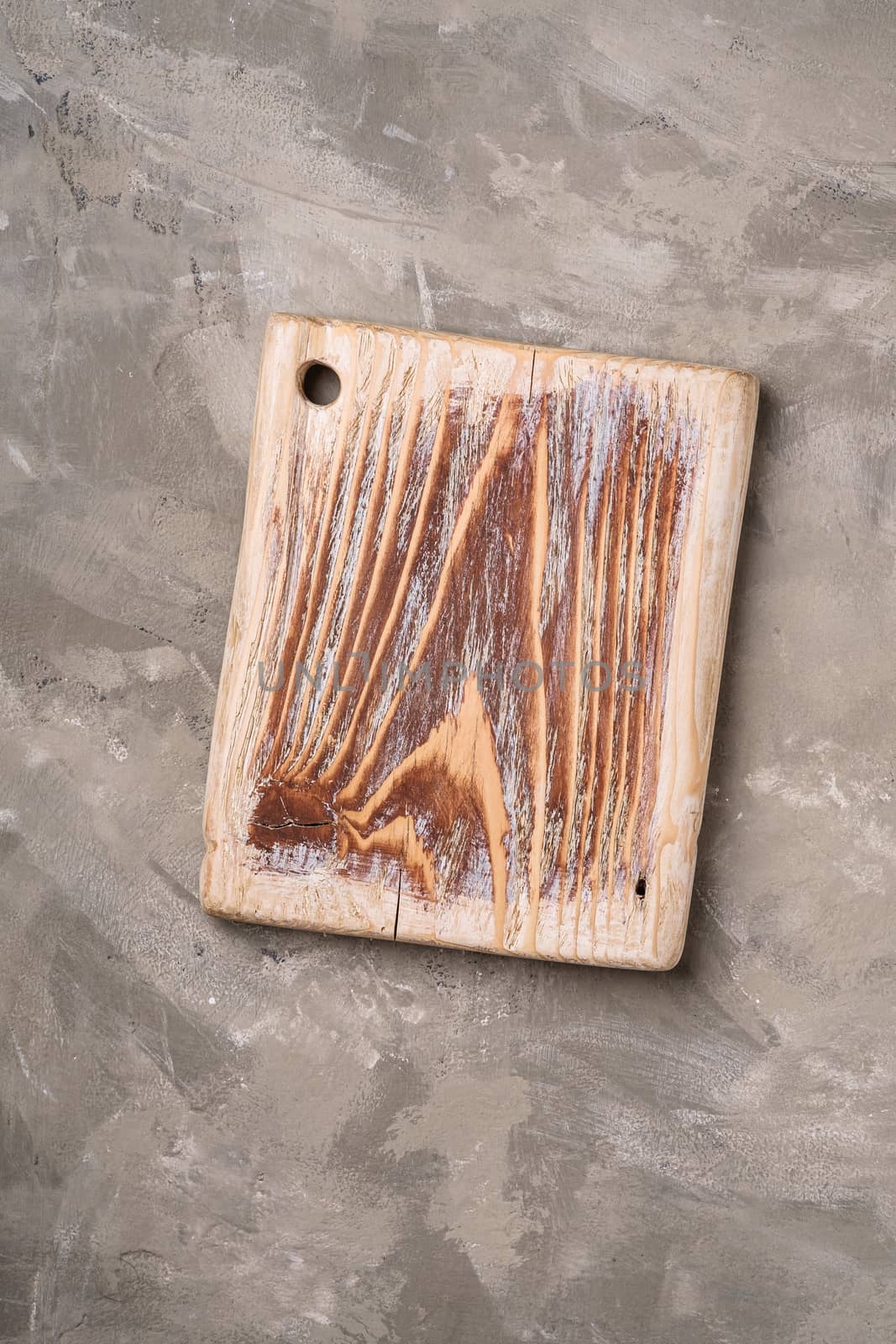 Handcrafted old wooden cutting board on stone concrete background, top view