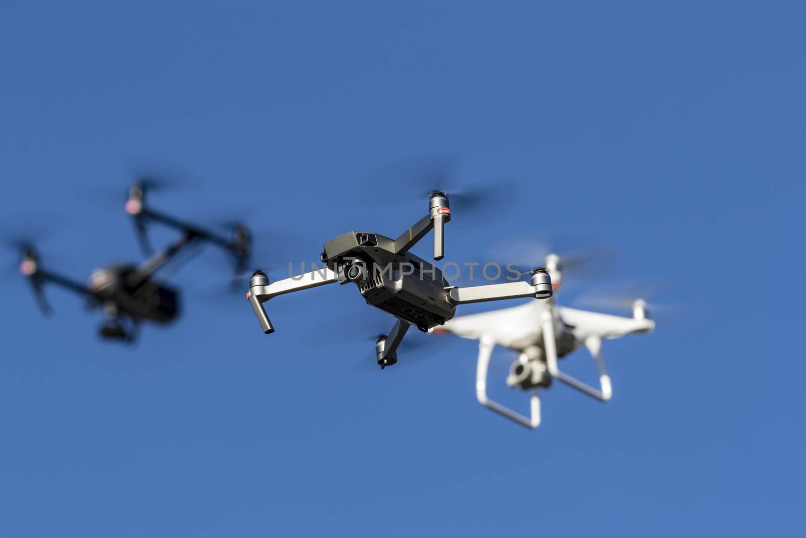 A group of drones fly through the air against a blue sky