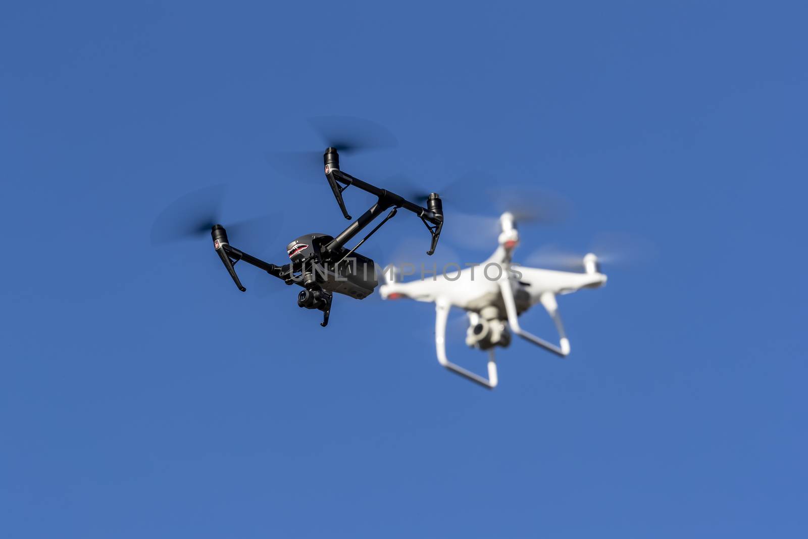 A group of drones fly through the air against a blue sky