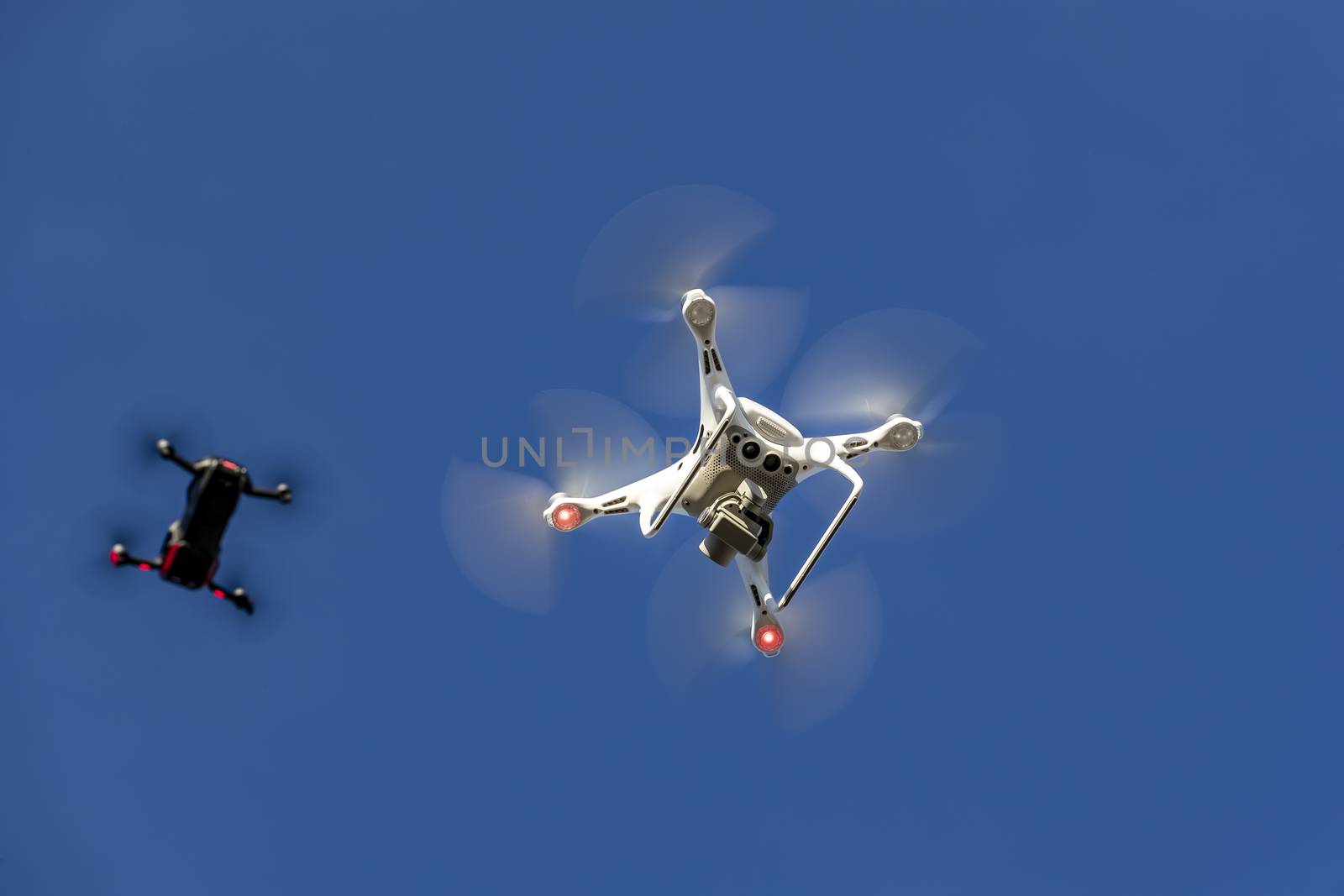 A group of drones fly through the air against a blue sky