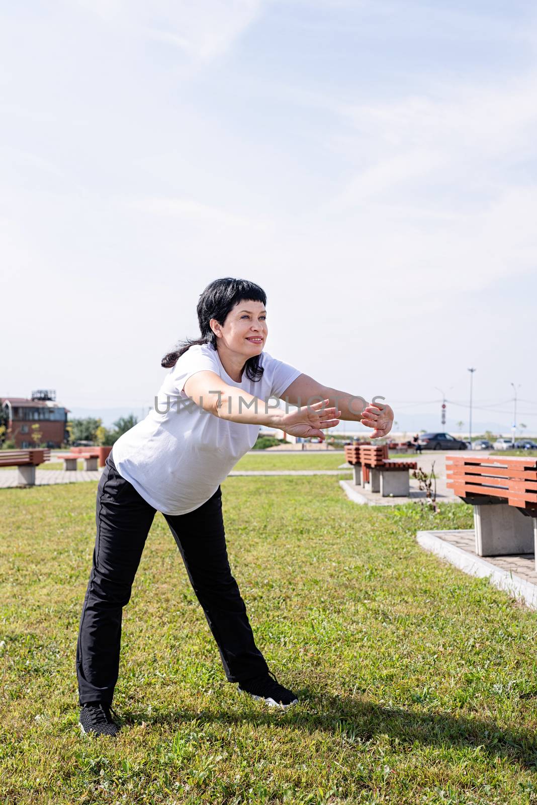 Sport and fitness. Senior sport. Active seniors. Smiling senior woman warming up stretching outdoors in the park