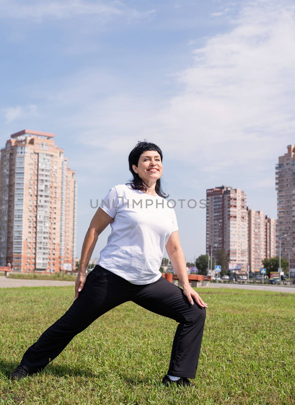 Sport and fitness. Senior sport. Active seniors. Smiling senior woman warming up stretching outdoors in the park