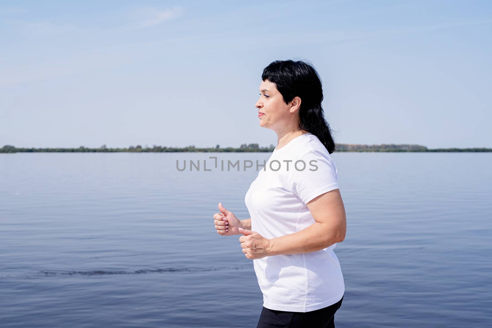 Active senior woman jogging near the riverside by Desperada