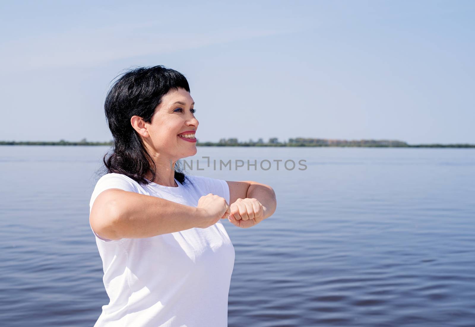 Active and happy senior woman exercising near the riverside by Desperada