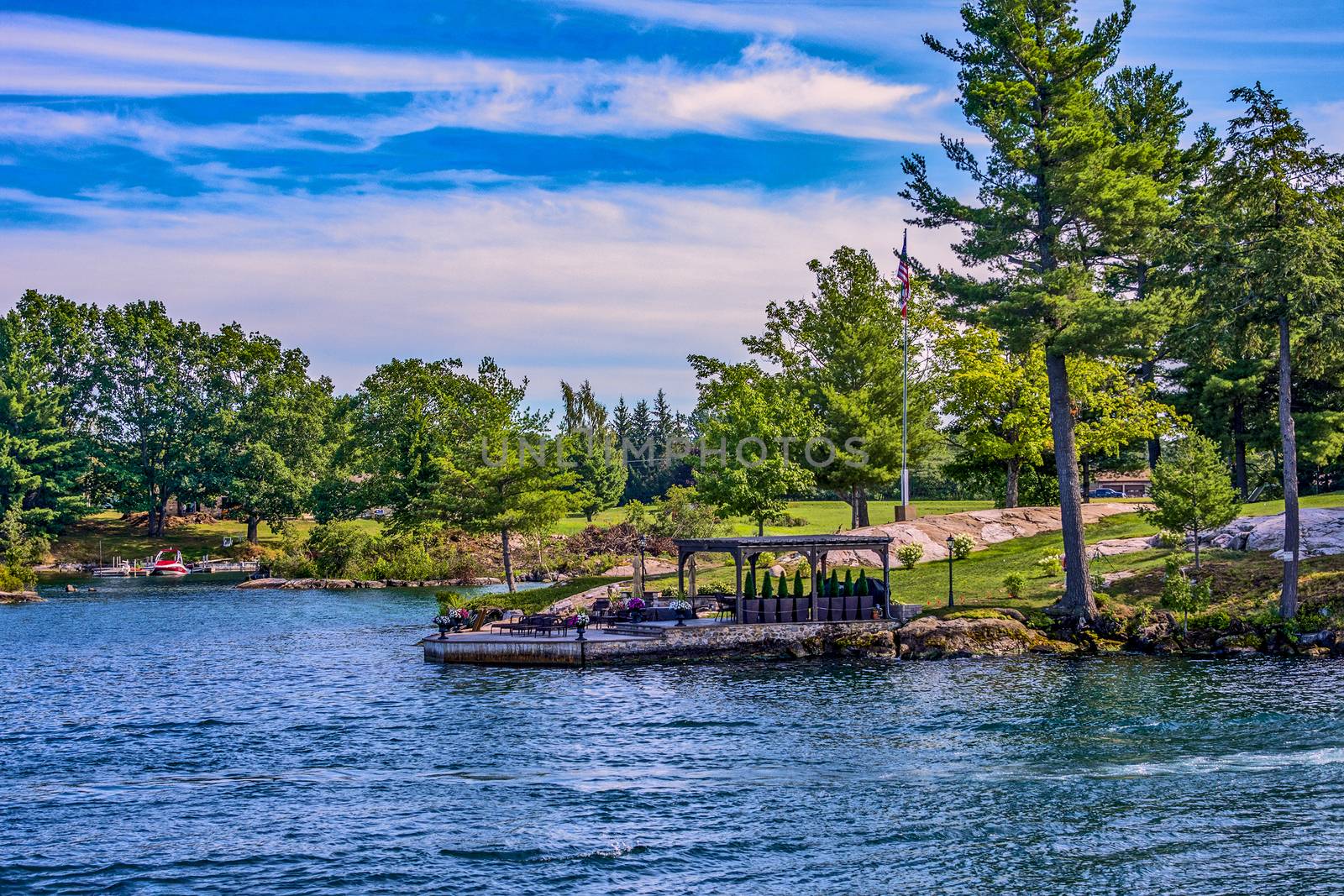 A boat dock on the island decorated with flowerpots, with a canopy and a table ready to receive guests