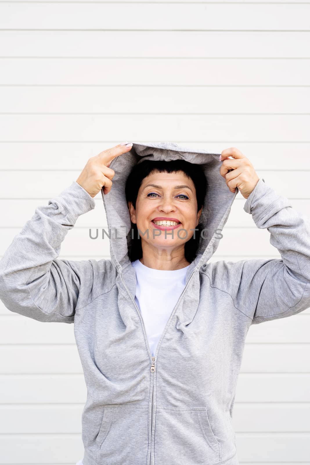 Senior woman waring gray jacket standing outdoors on gray solid background by Desperada