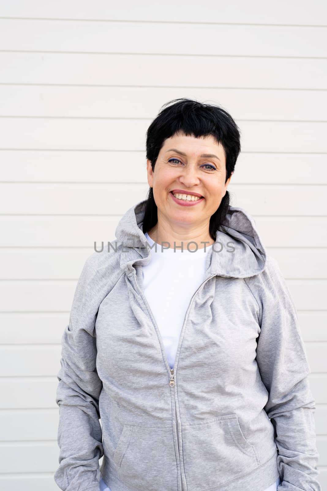 Senior woman waring gray jacket standing outdoors on gray solid background by Desperada