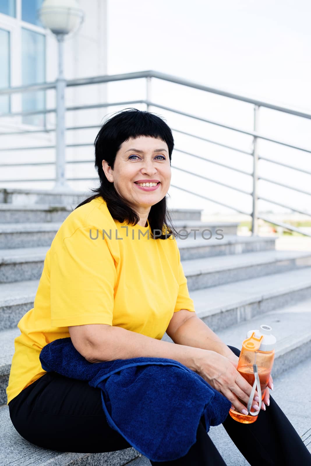 Sport and fitness. Senior sport. Active seniors. Smiling senior woman drinking water after workout outdoors on urban background