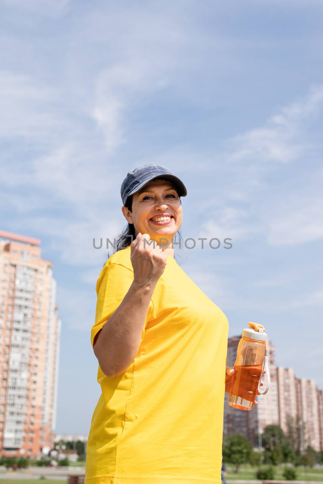 Sport and fitness. Senior sport. Active seniors. Excited senior woman drinking water after workout outdoors on the sports ground