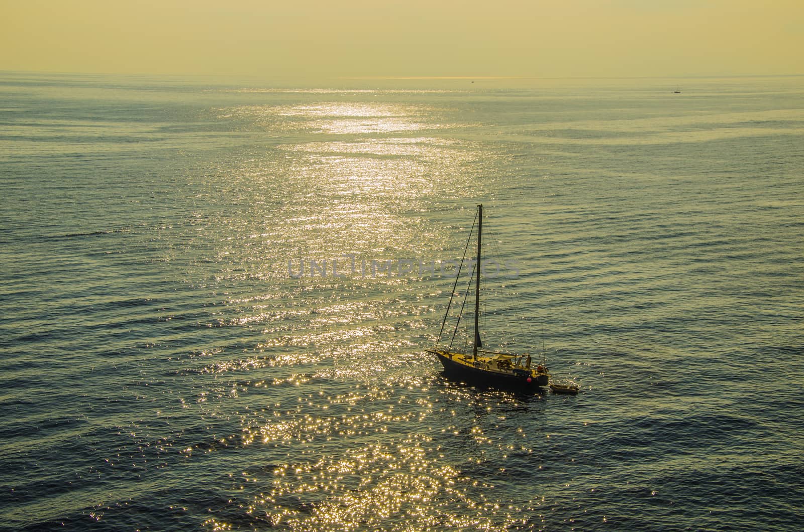 Sunset and sailboat accompanied by his boat in peaceful waters in the Tyrrhenian Sea