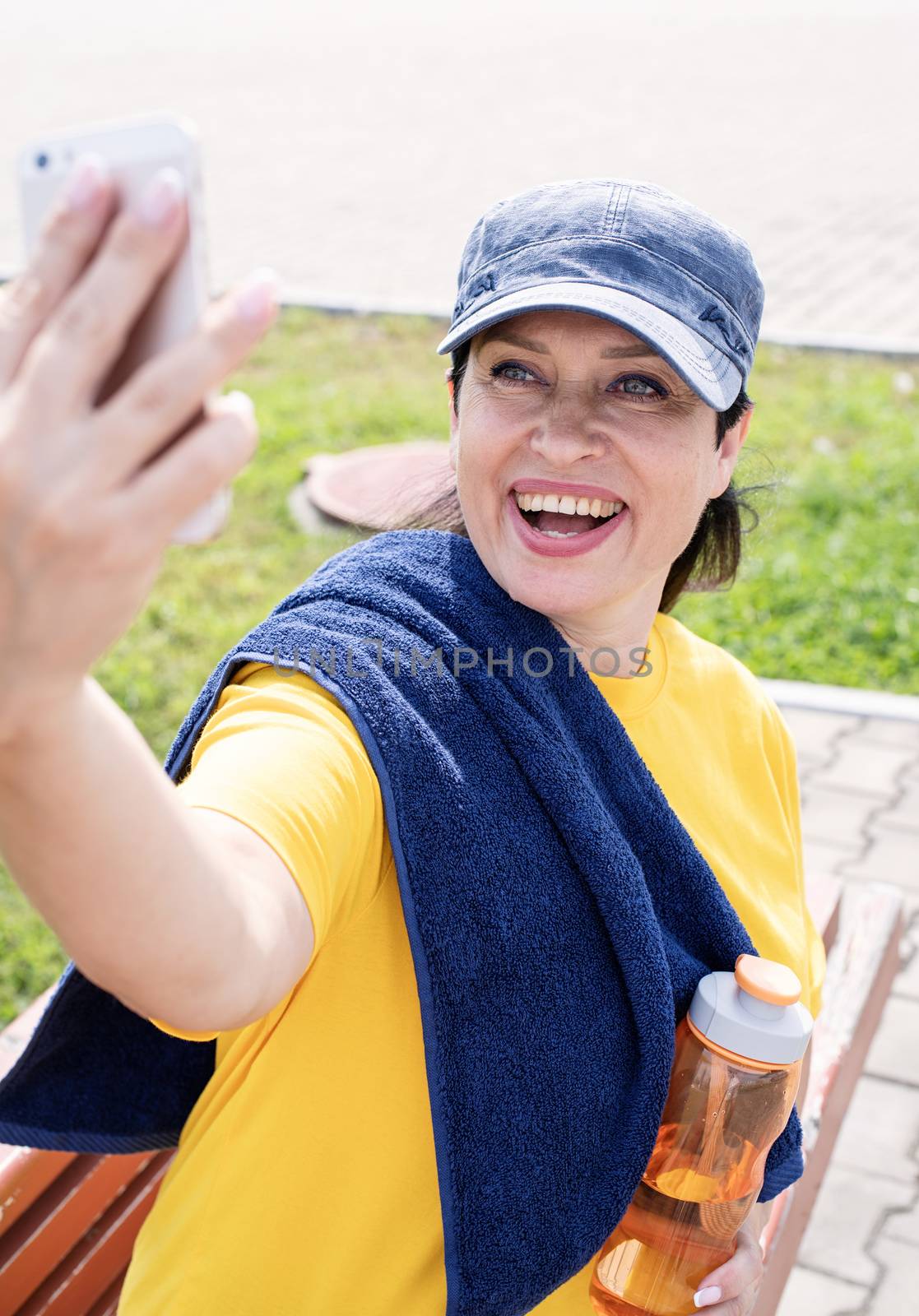 Smiling senior sportswoman doing selfie outdoors in the park by Desperada