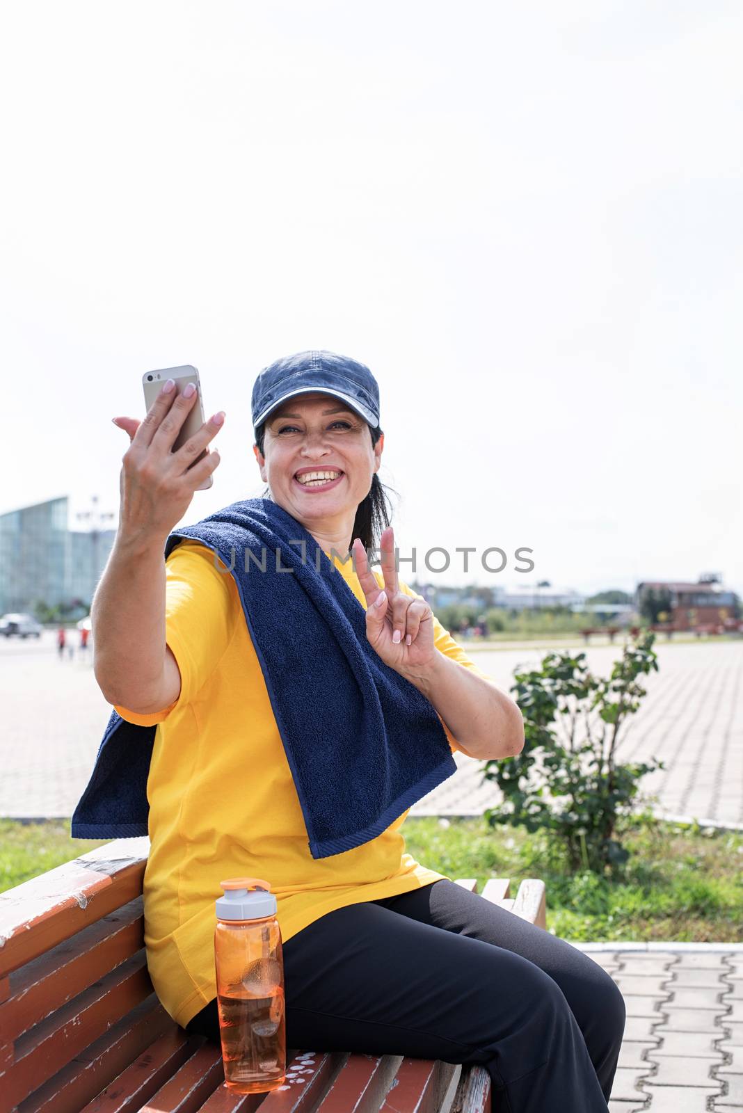 Sport and fitness. Senior sport. Active seniors. Smiling senior sportswoman doing selfie outdoors in the park