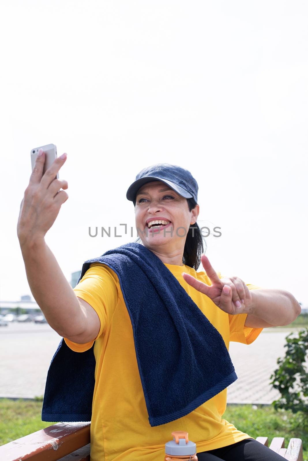 Sport and fitness. Senior sport. Active seniors. Smiling senior sportswoman doing selfie outdoors in the park