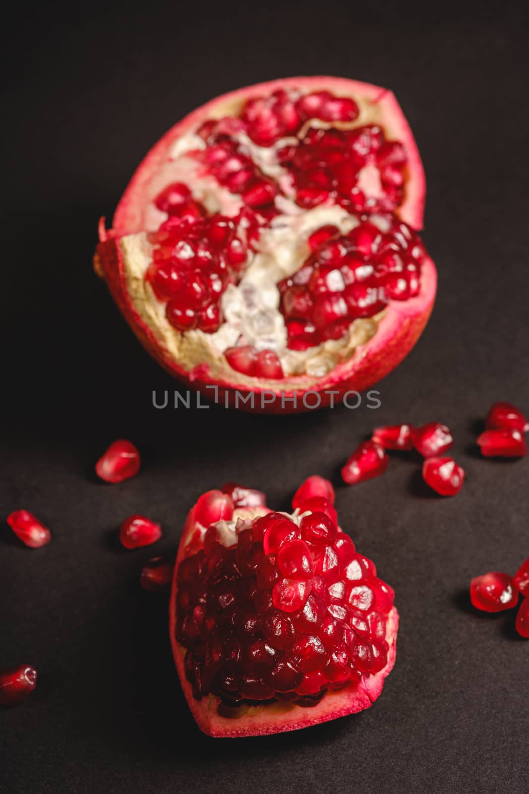 Fresh tasty sweet peeled pomegranate with red seeds on dark background