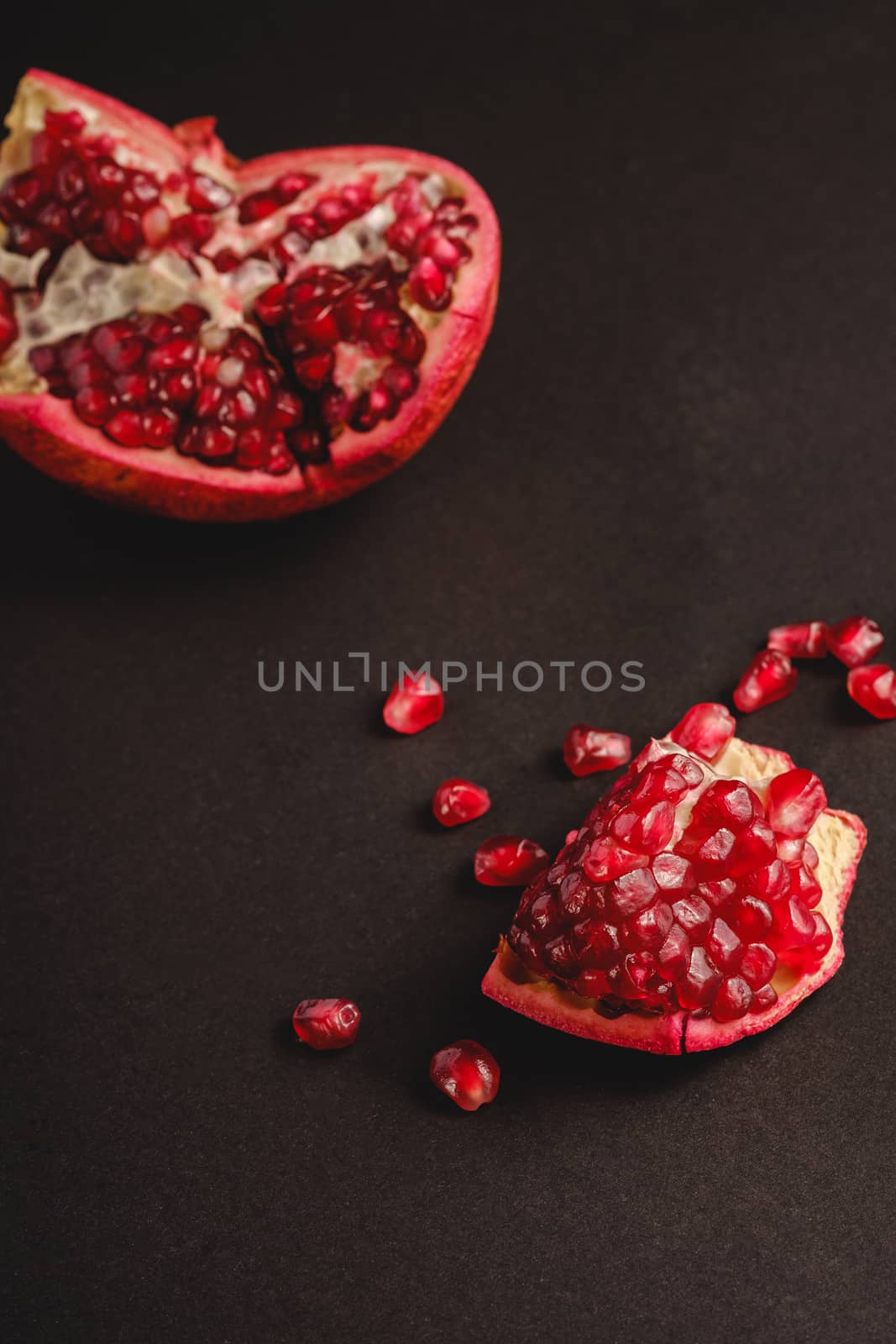 Fresh tasty sweet peeled pomegranate with red seeds on dark background