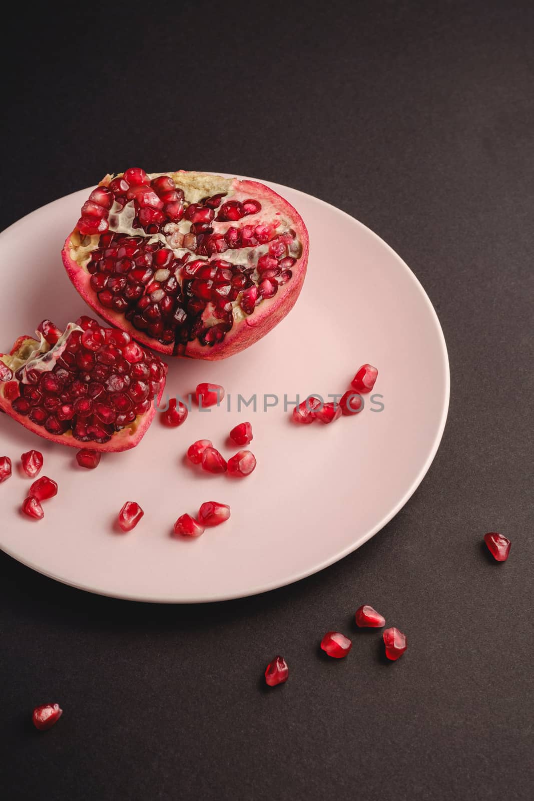 Fresh tasty sweet peeled pomegranate with red seeds on dark background