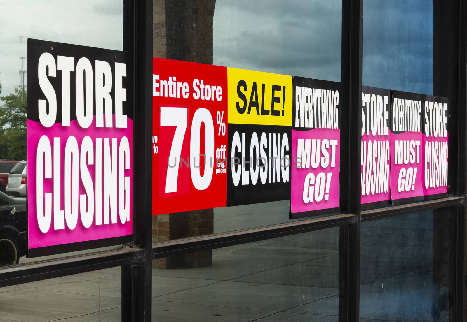 Horizontal shot of Going Out of Business signs in a retail store’s windows.