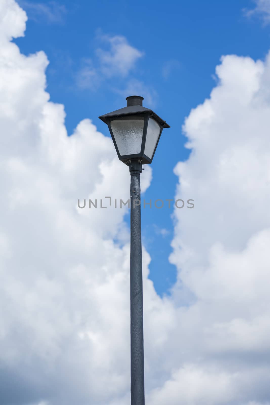 Vertical shot of a lamppost against a blue cloudy sky.