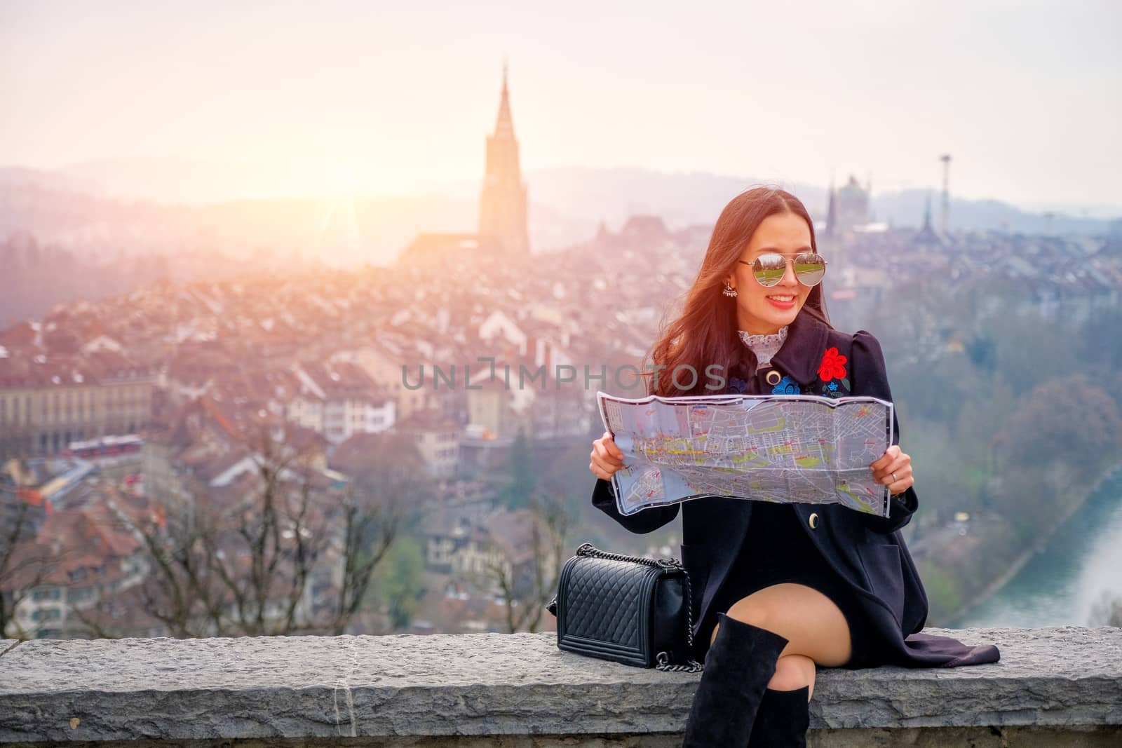 Young female tourist with map looking for a way to Beautiful view point near old town in Bern, Switzerland
