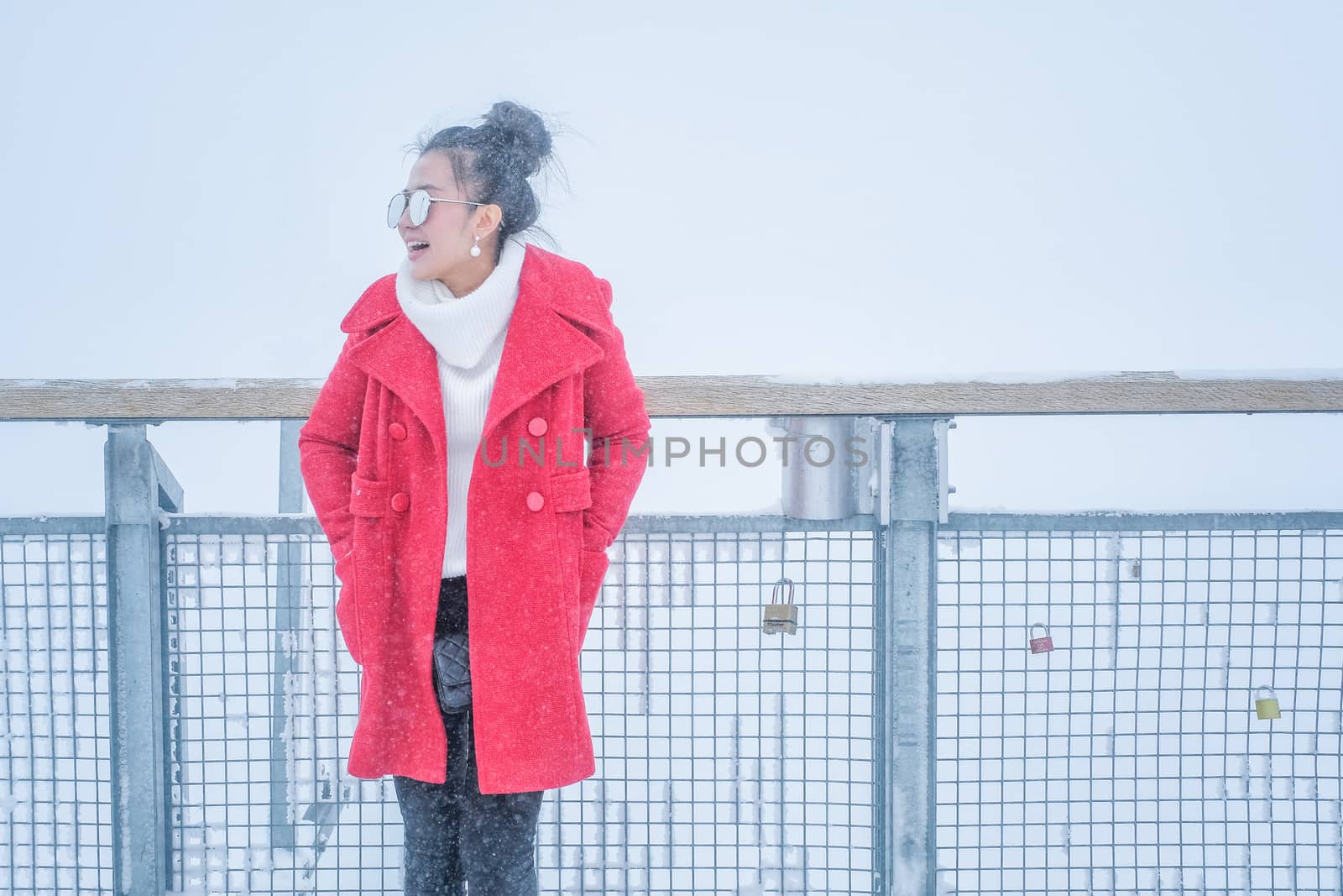 Beautiful young woman playing with snow in fur red coat outdoors