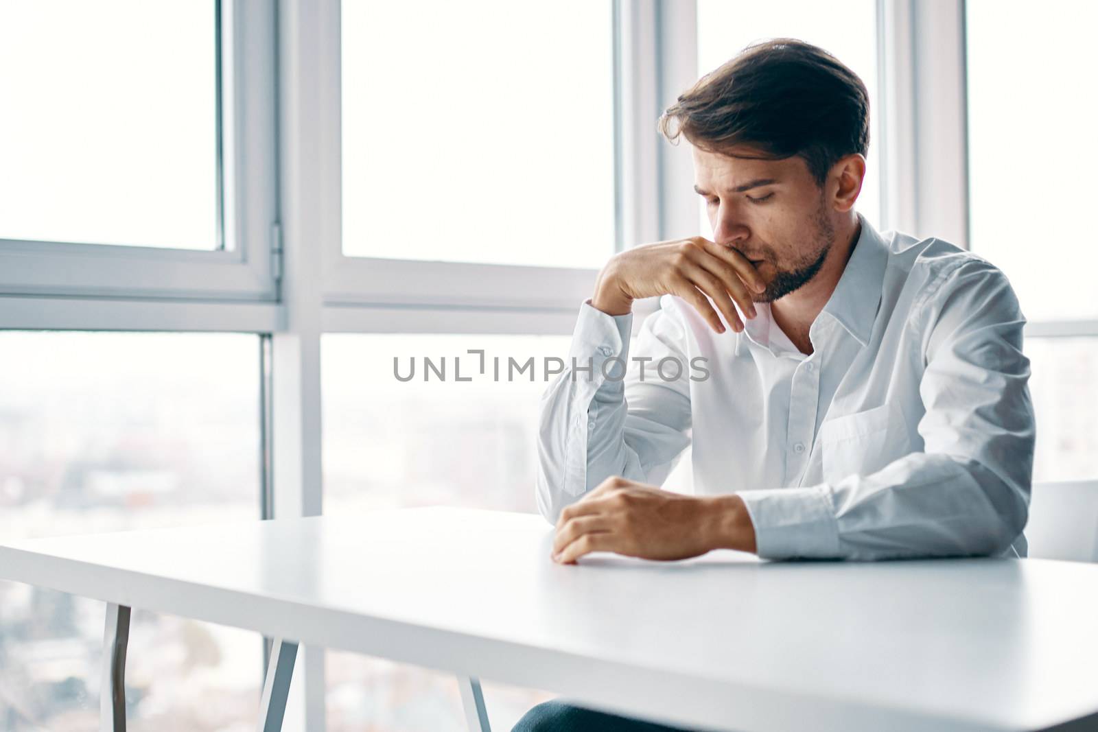 sad man of european appearance at the table indoors at work