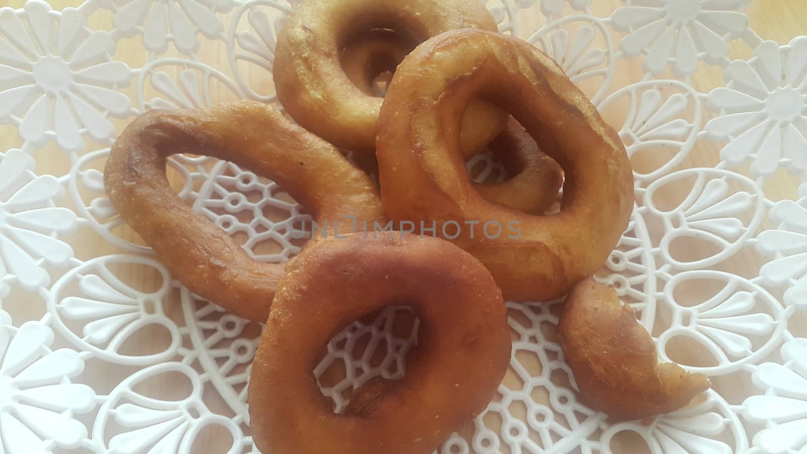Closeup view of a set of freshly prepared donuts served on white changair. Donuts are placed in a changair over wooden floor