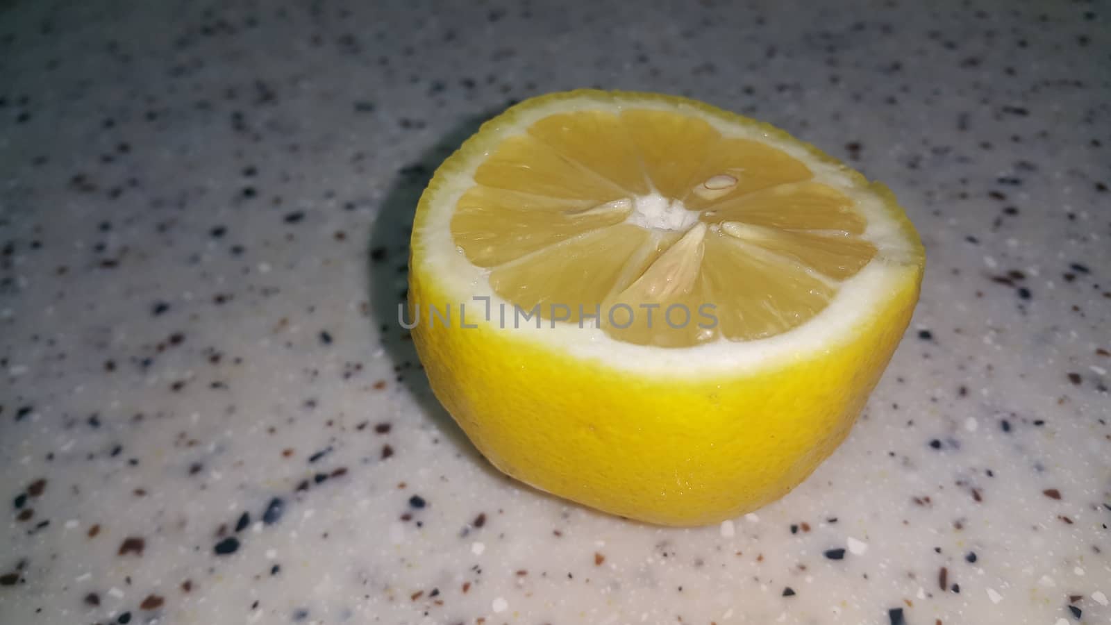 Fresh lemon slices with yellow peelings placed on a grey floor. Top view of fresh juicy lemon slice background