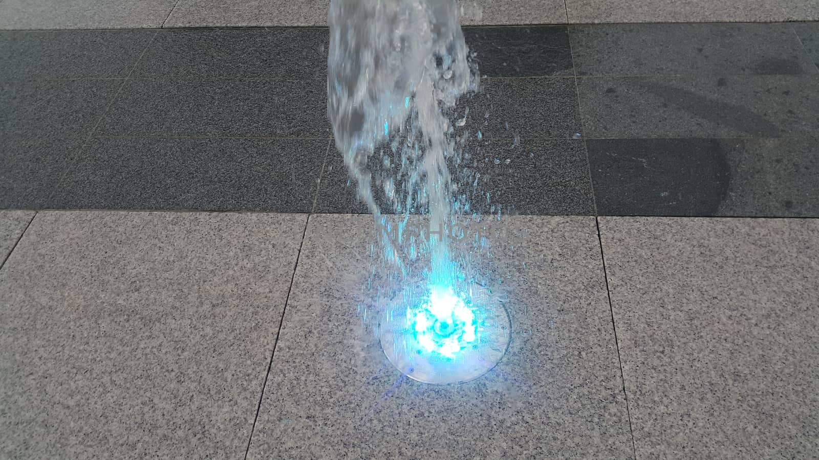 Beautiful and colorful light water fountain over concrete floor by Photochowk