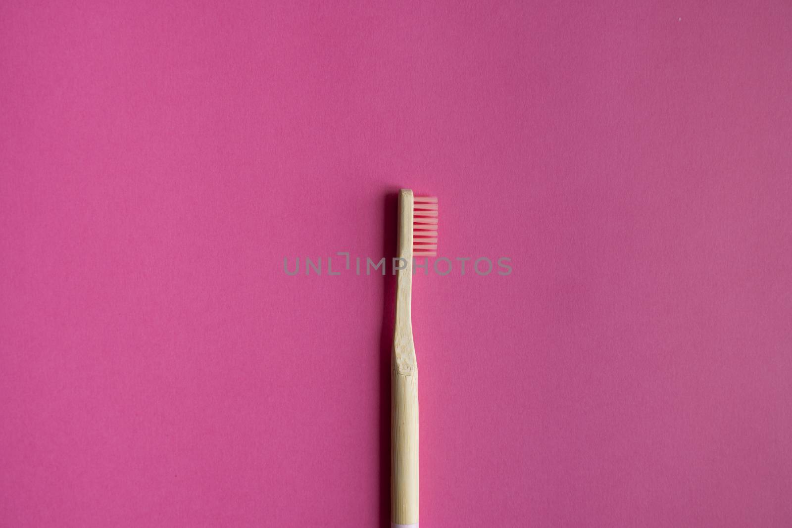 Eco-friendly bamboo toothbrush on a pink background. Zero-waste. Biodegradable toothbrush. by vovsht