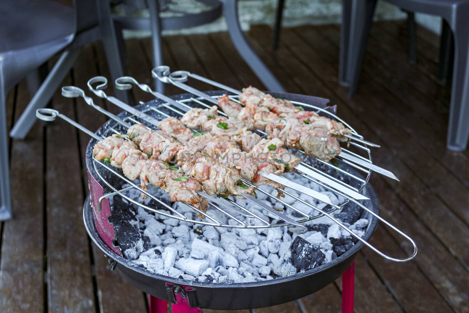 Russian shashlik with skewers on a round grill in Norway.