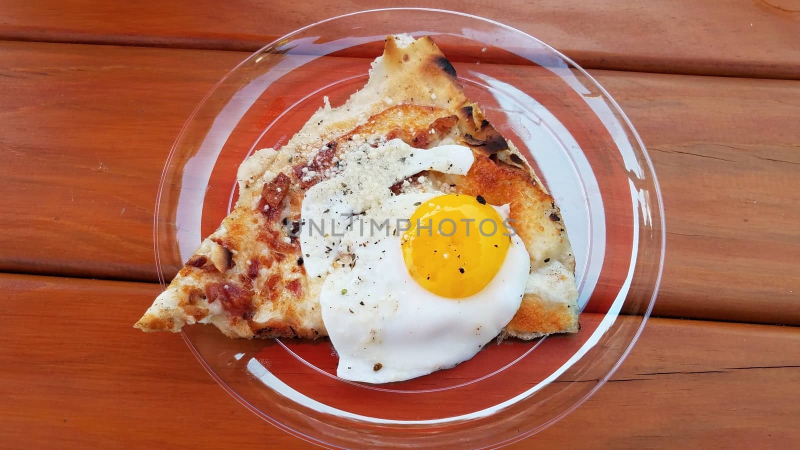 egg and bacon breakfast pizza on plate on wood table