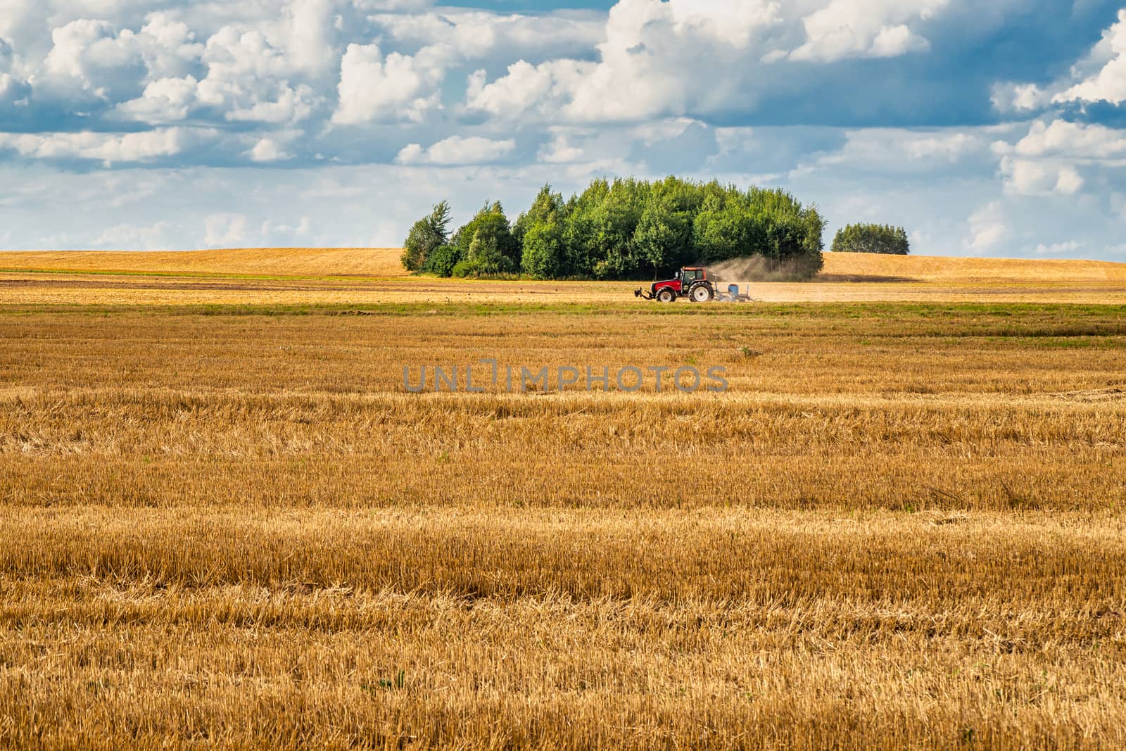 Cultivated Land in The Countryside with Tractor and Blue Sky Background.