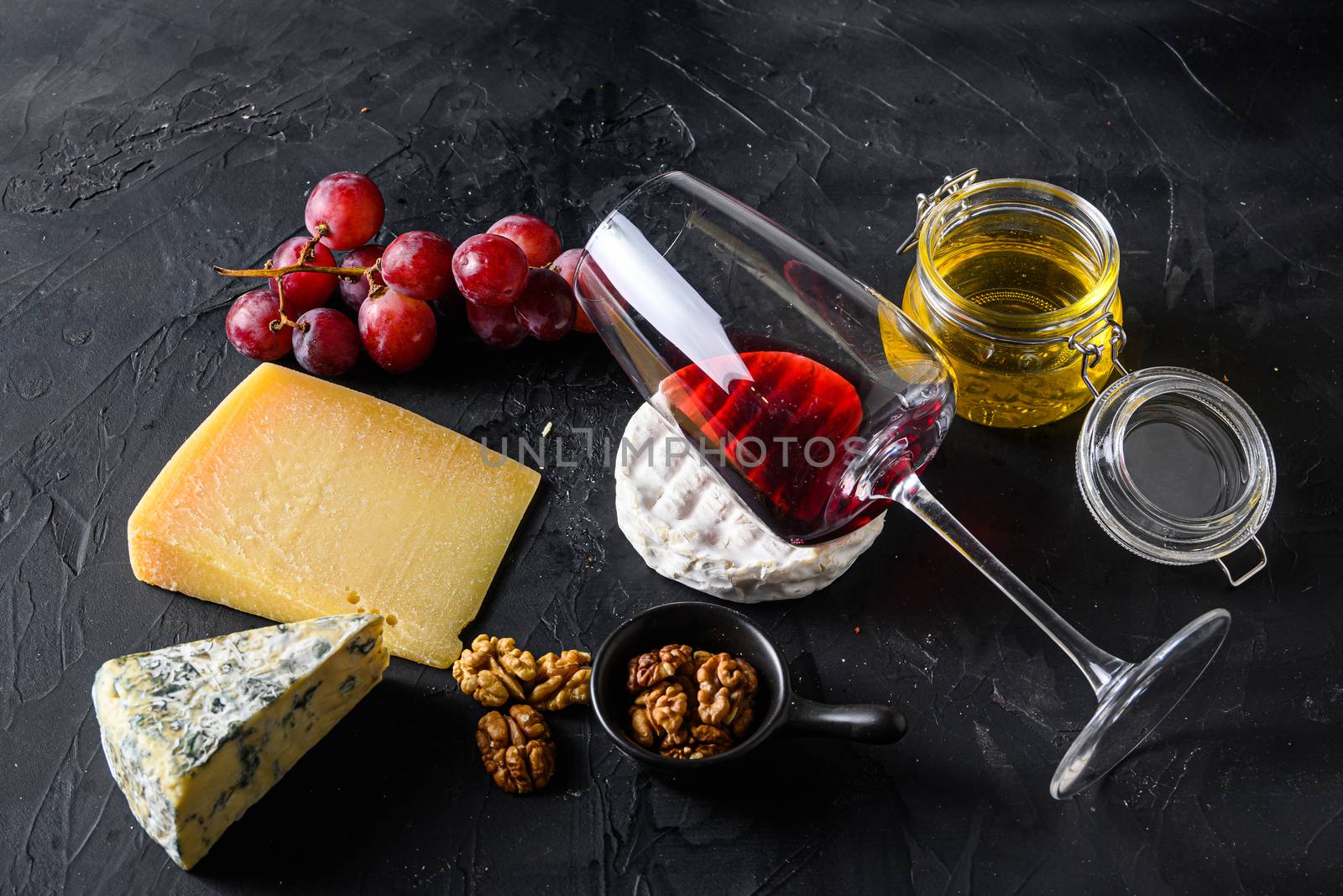 Grapes, red wine, cheeses, honey and nuts side view red merlot wine in glass antipasto.