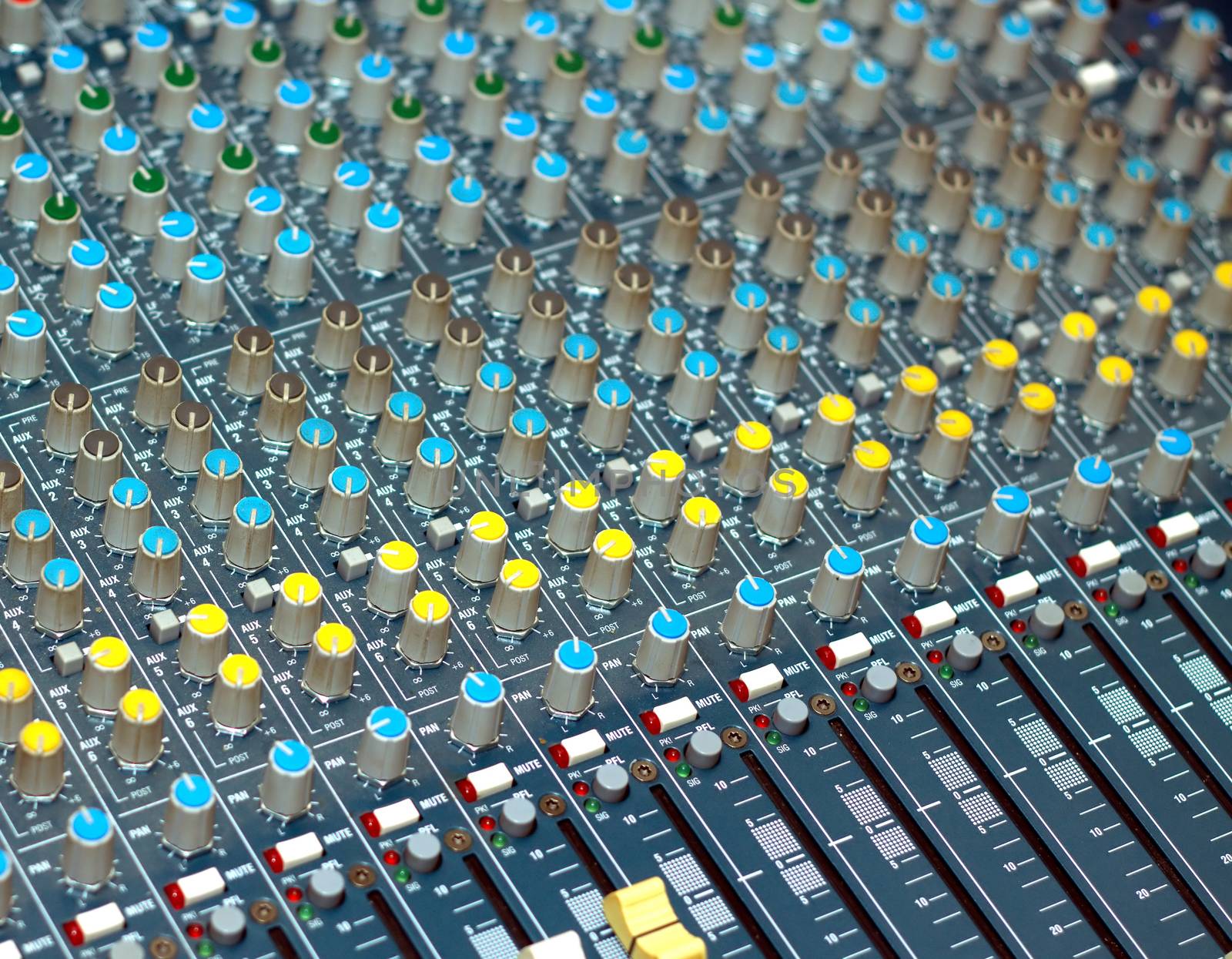 Big multichannel audio sound mixer with many buttons and knobs diagonal view closeup