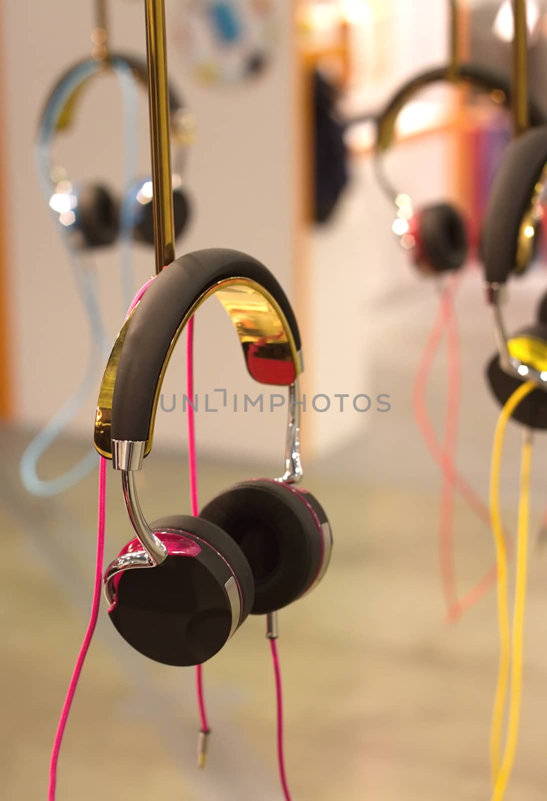 Many color stereo headphones hangs on stand vertical view closeup
