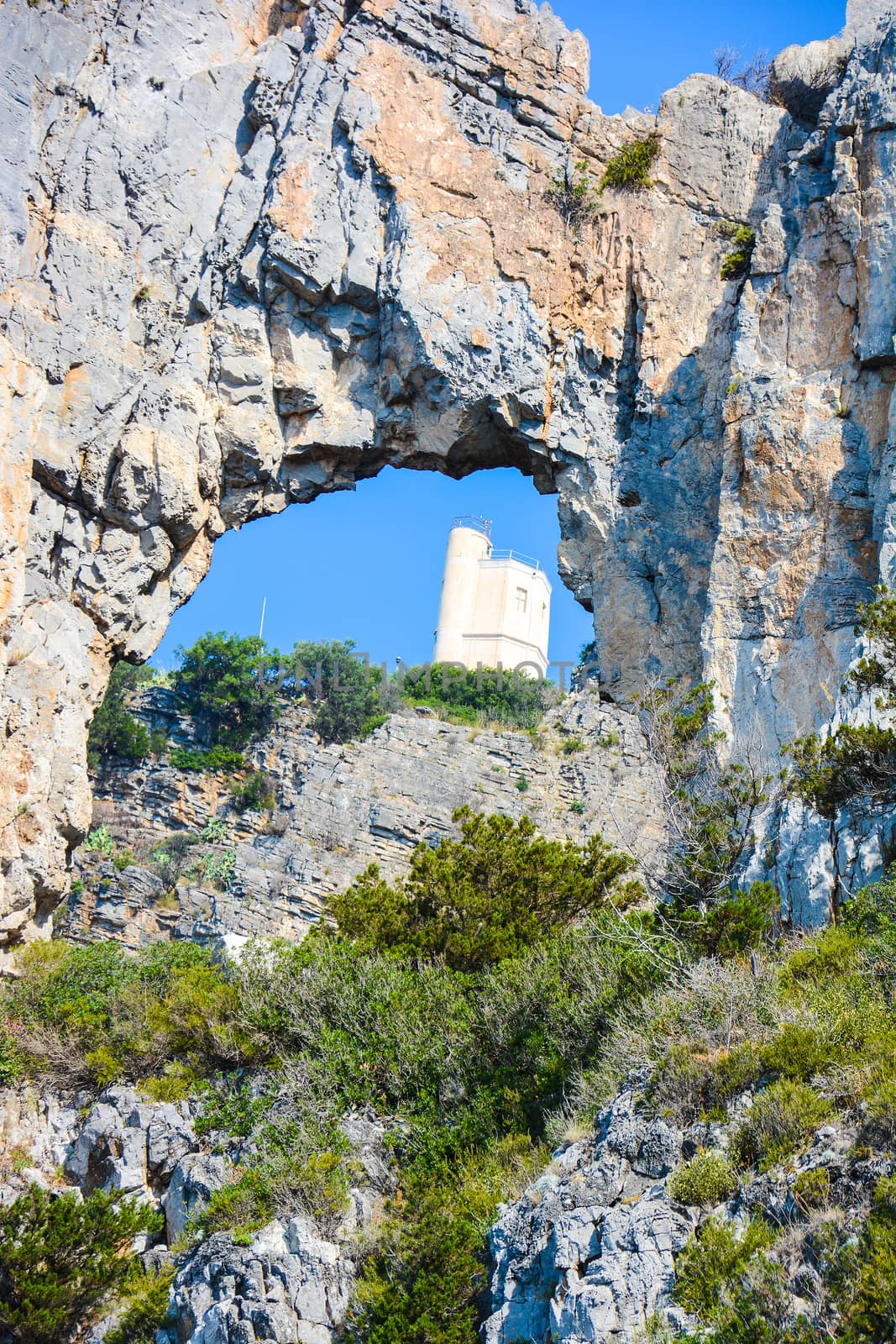 view of the Saracen tower restored through the natural ring of the cliff at Palinuro in Italy